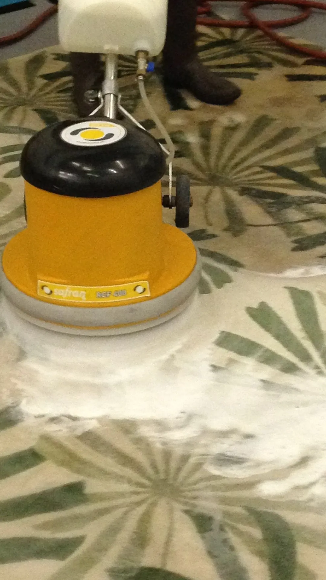 Rotary shampoo machine working foam through a patterned rug