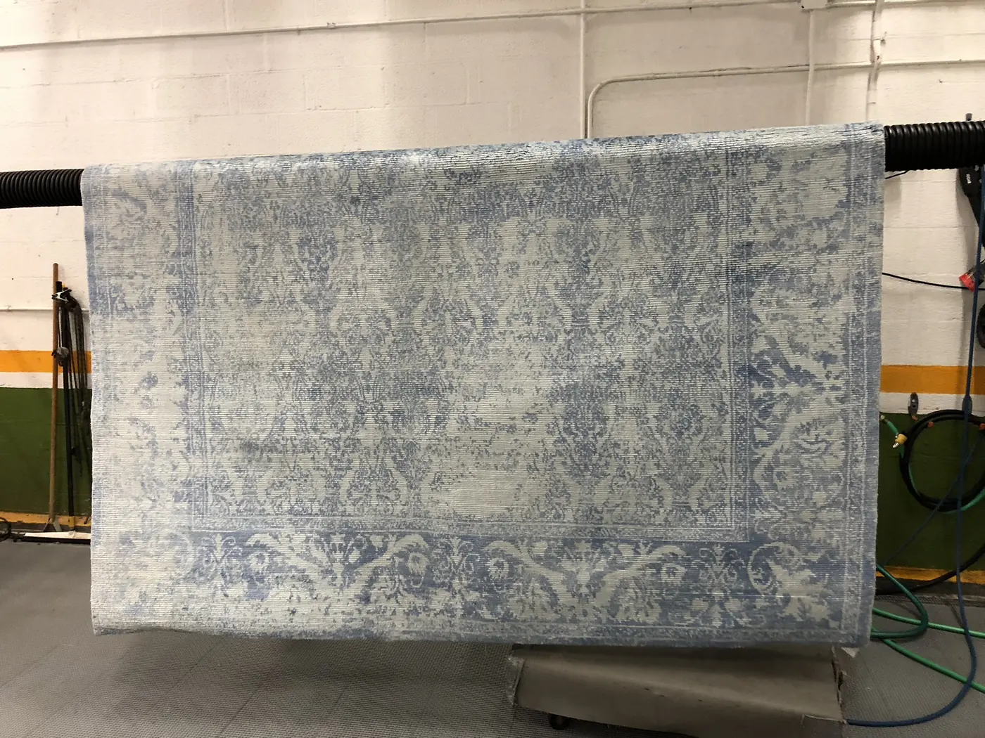 Large pale blue-grey rug hanging on the drying rack