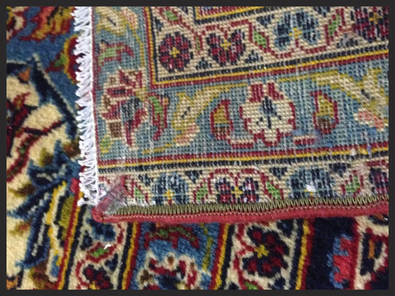 Back of an Oriental rug showing a damaged serged edge before repair