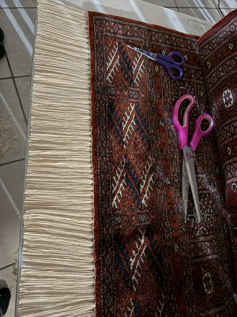 Scissors and repair thread resting on a tribal rug at the bench